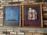 Both framed posters side by side on brick wall