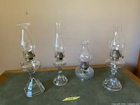 Front view of all four glass oil lamps on table