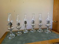 Front view showing all six clear glass oil lamps side by side