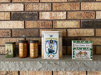 Five tins lined on mantle, showing size and graphics