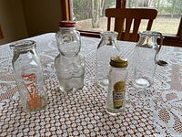 Group shot of six vintage glass containers on lace tablecloth