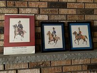 Calendar and two framed prints displayed on mantel