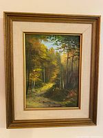 Framed oil painting showing autumn forest scene, signature visible