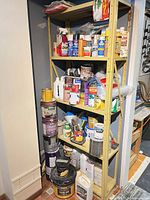 Full view of metal shelf with paints, propane torch, respirator, aerosols