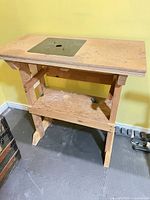Full view of wooden router table showing frame, top, and shelf
