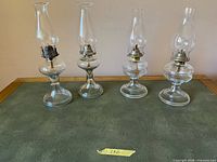 Four oil lamps on surface showing overall condition and pair differences