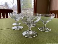 Six crystal dessert bowls showing etched grapevine design and footed stems