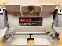 Front view of ShopCraft 5" bench grinder showing label and grinding wheels