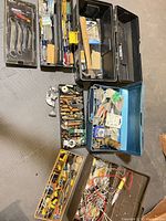 Group of toolboxes open displaying wrenches, screwdrivers, plumbing and electrical supplies