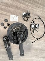 All parts laid out: crankset, crank arm, shifter, derailleur, caps