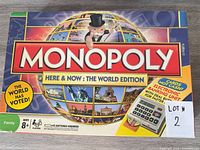 Front lid showing Monopoly Here & Now: The World Edition branding and electronic banking graphic