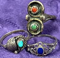 Close-up of three silver rings displaying stone settings and designs