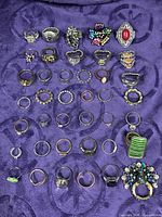 Full lot of rings arranged on purple fabric showing quantity and variety