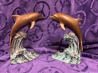 Front view of both bronze dolphin bookends showing overall form and finish
