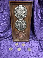 Framed print with three enlarged replica coins and five Eisenhower dollars below