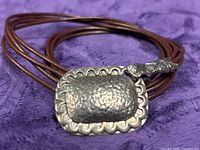 Close-up of hammered sterling pendant on leather strands