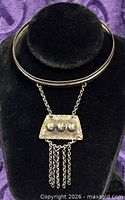 Front view of silvertone collar necklace with pendant and chain tassels
