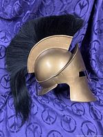 Left side view of bronze-tone Spartan helmet showing full crest and face guard