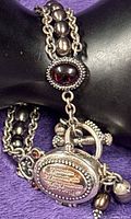 Close view of watch case, garnet, toggle clasp, charms