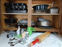 Cabinet shelves loaded with assorted bakeware and front counter with baking tools