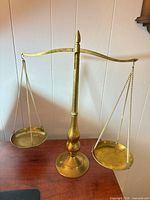 Front view of brass balance scale showing both pans and central column