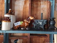 Shelf view showing stoneware jug, ceramic dog figurine, two cast iron stoves