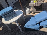 stacked blue cushions on white plastic patio table outdoors