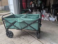 Side view of green fabric folding wagon on black metal frame