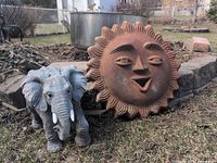 Sun face plaque and resin elephant set in outdoor setting