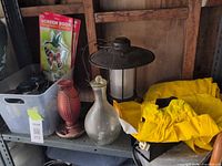 Shelf with Coopower lantern, glass wasp trap, hummingbird feeder, timer, decals, rainsuit and tub of small lanterns