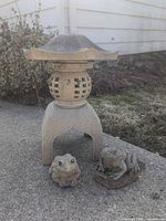 Pagoda assembled next to two frog statues, outdoor setting