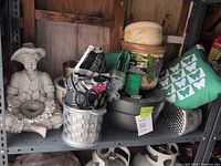 Entire shelf showing statue, multiple pots, planters, cushion and supplies