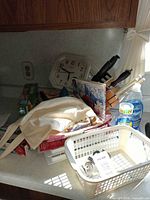 overall lot on countertop with knife block, cookbooks, clock, dish soap, food wrap boxes, cloth bag