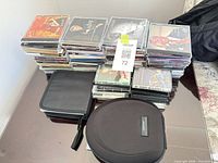 Overall lot showing Bose case, soft pouch and stacks of CDs