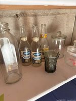 Group showing milk bottle, three Labatt beer bottles, green pressed-glass vase, and two lidded jars
