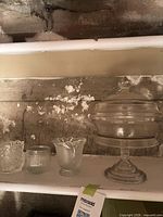 Group view of pedestal dish and three candle holders on shelf