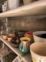 Shelf with multiple planters, bud vases, glass vases and tub of marbles