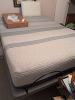 Full view of queen adjustable bed with mattress, remote and accessory box visible