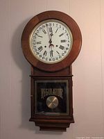 Front view of wall regulator clock showing full case and lower glass door