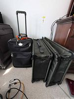 Black Air Canada suitcase beside two folded Tutto portfolio cases