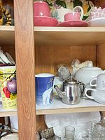 Shelf with blue polar bear mug, stainless mini teapot, white teapot and other mugs