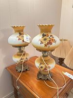 Two matching sunflower milk glass table lamps on table