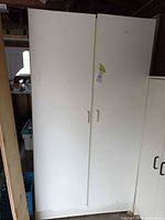 Front view of white pressboard wardrobe, closed double doors, handles visible