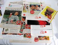 Assorted Coca-Cola and 7Up magazine ads arranged on table