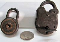 Two padlocks side by side with coin for scale; key inserted in Pinson lock