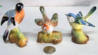 Front view of the three bird figurines with coin for scale