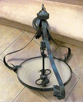 Full view of chandelier showing wrought iron frame, frosted glass bowl, hanging loop and canopy
