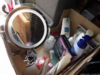 Overall view of vanity mirror and toiletries inside cardboard box