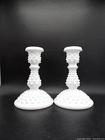 two hobnail milk glass candle holders upright