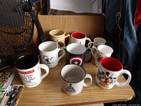 Nine mugs arranged on shelf showing variety